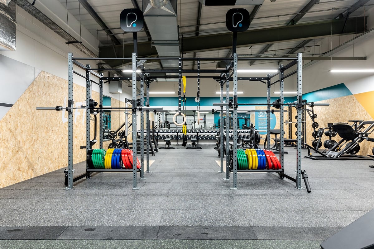 PureGym Alloa: Rig with squat racks, weight plates, bars, and rubberized floors - functional training setup.