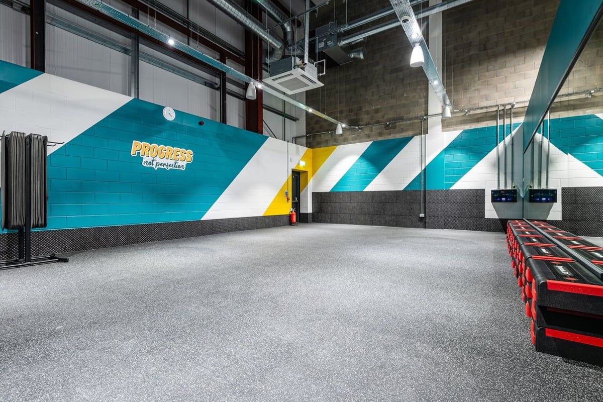 PureGym Elgin: Bright studio space with padded floors, angled mirrors, and functional training equipment.