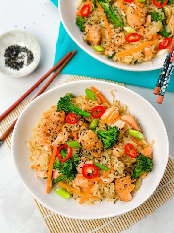 Noodles with salmon, broccoli, carrot, red chili, spring onion, and black sesame seeds in