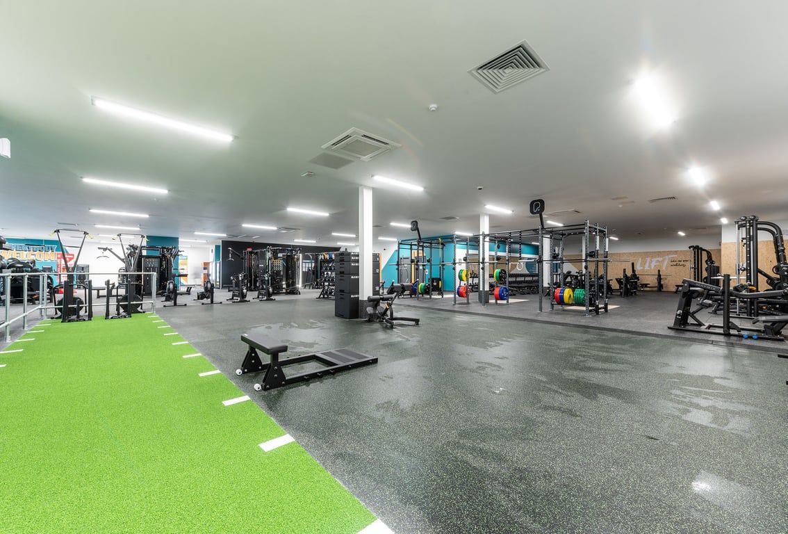 PureGym Knaesborough: Racks, benches, weights, turf area, and rubberized flooring of a well-equipped gym space.