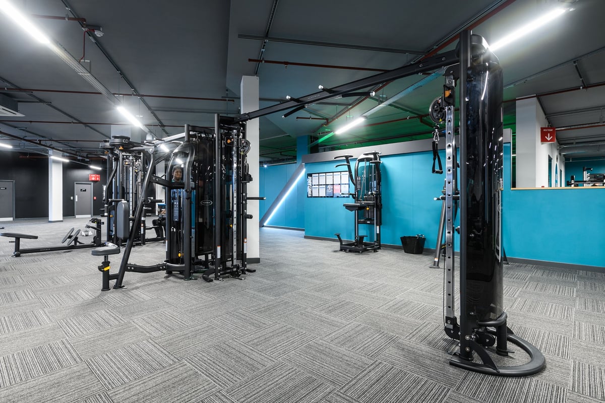 PureGym Basildon: Cable machines, squat racks, weight benches, barbells, rubberized flooring in gym studio.
