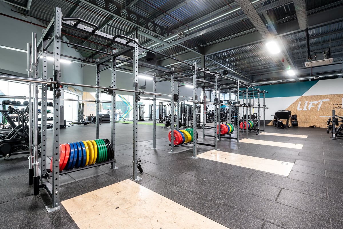 PureGym Peterborough Serpentine Green Shopping Centre: Gym with squat racks, weight plates on racks and rubberized flooring.