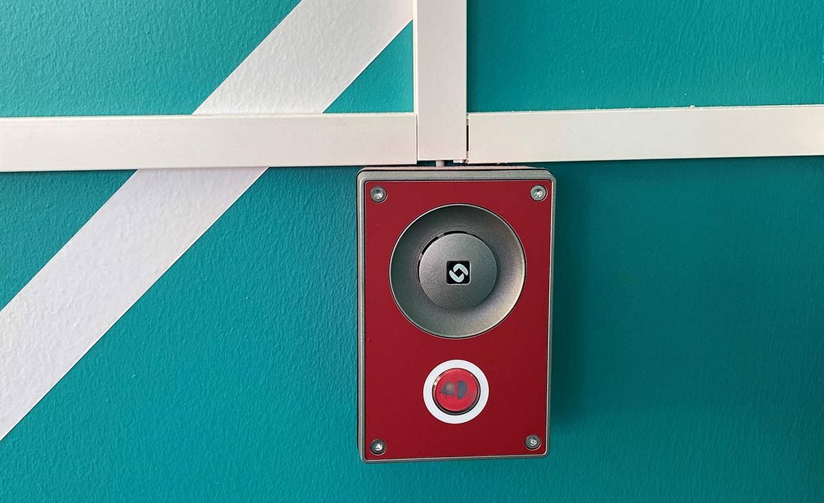 Red emergency help point on the gym wall with 2-way communication button.