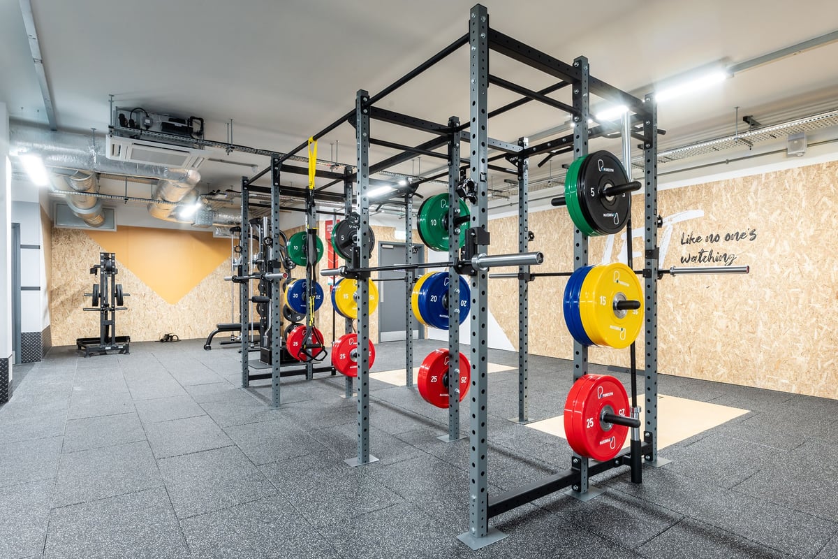 PureGym London Swanley: Squat racks, weight plates in multiple colours, and rubberized flooring in a gym setting.
