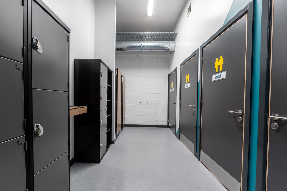 PureGym Dungannon: Rows of metal lockers, grey doors, signage depicting human figures.