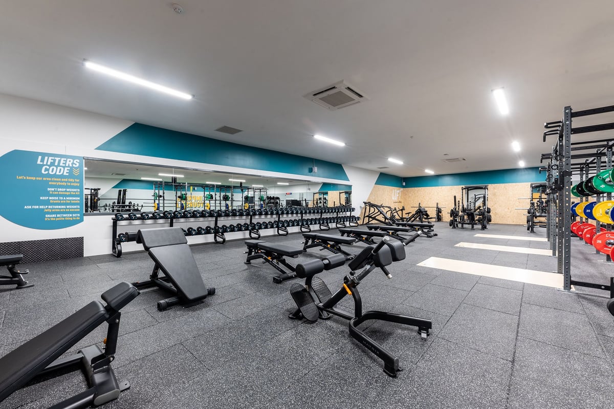 PureGym Selby: Weight benches, free weights, squat racks, and rubberized flooring in a gym interior.