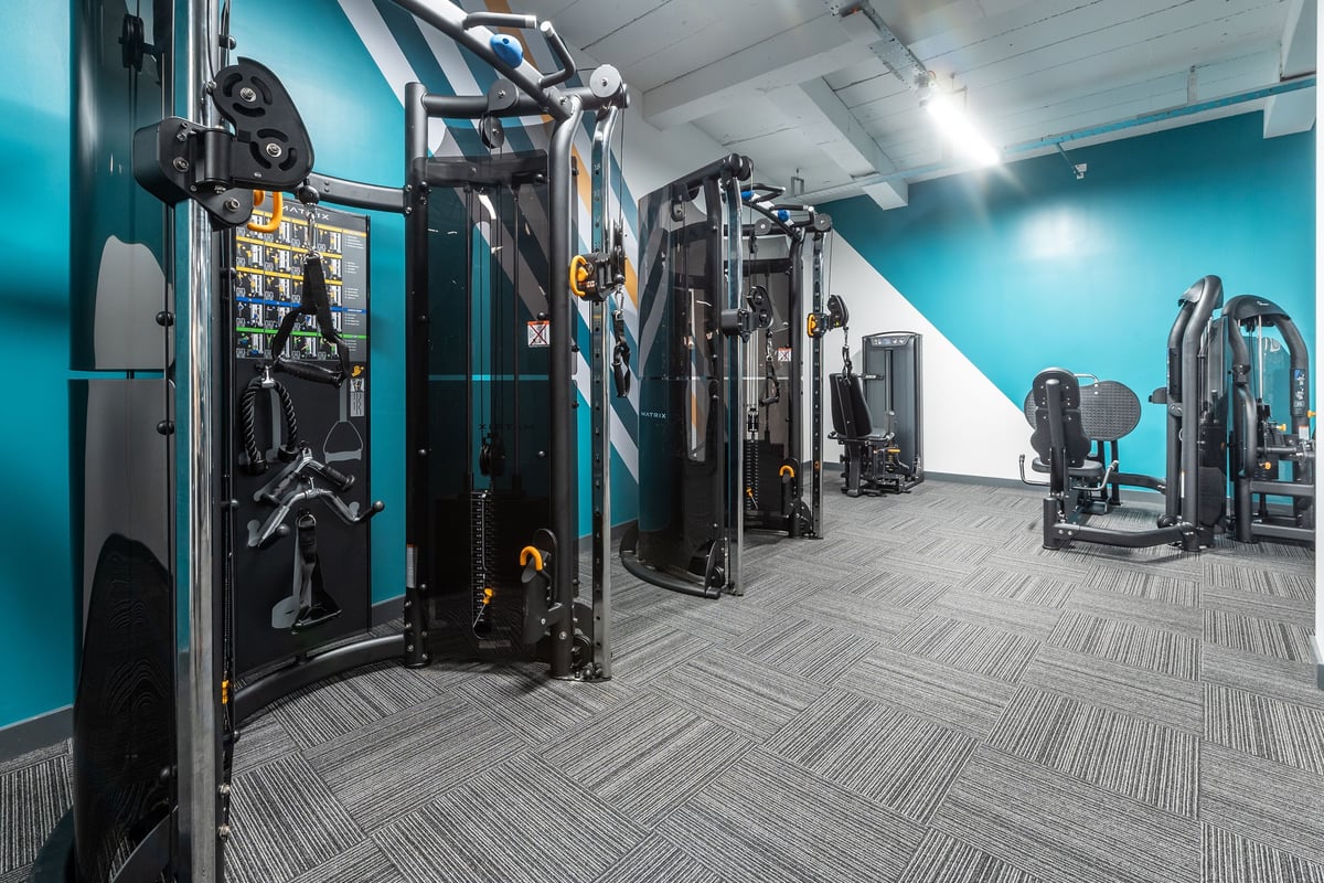 PureGym London Hornchurch: Rows of upright strength machines, screens, weights, and patterned rubberized flooring.