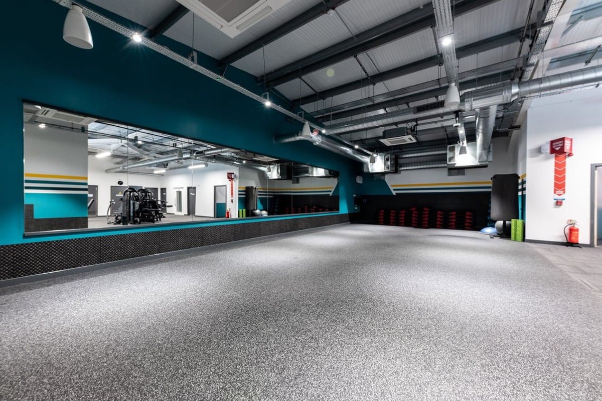 PureGym Galashiels: Rubberized gym floor, weight racks, treadmills, mirrored wall, ceiling-mounted lights.