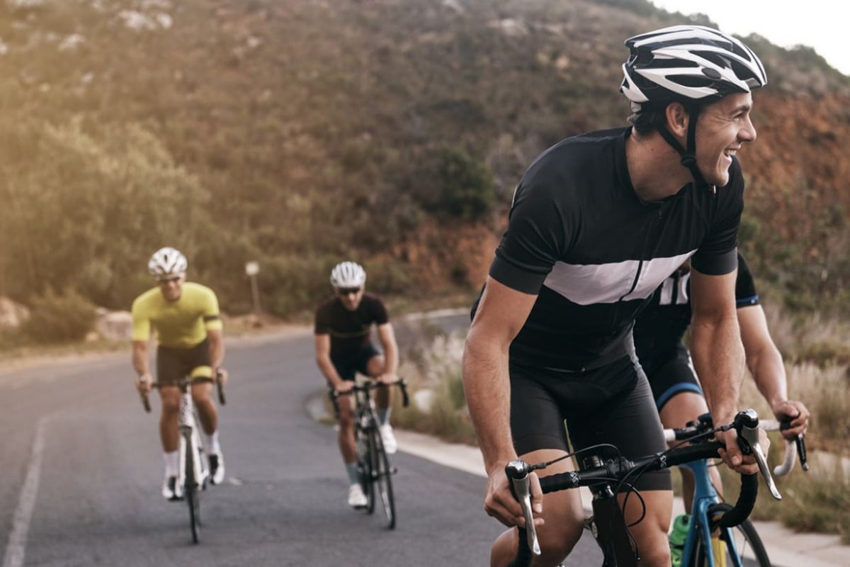 Gruppe von Radfahrern auf einer Bergstraße, Anführer trägt schwarz-weißes Trikot
