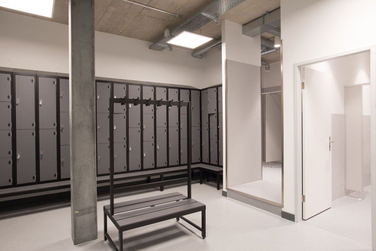 PureGym Adliswil: Vestiaire avec casiers métalliques, banquettes et cabines de douche privées.