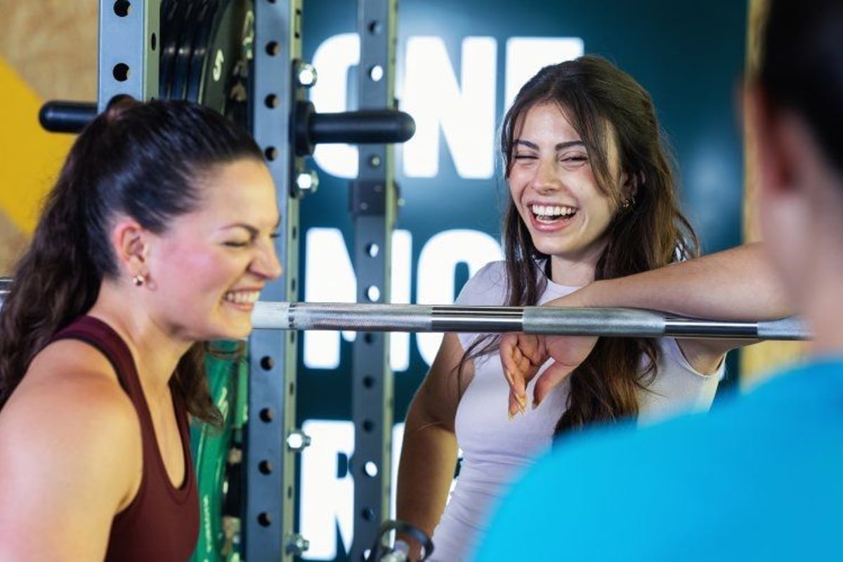 PureGym members laughing beside a squat rack