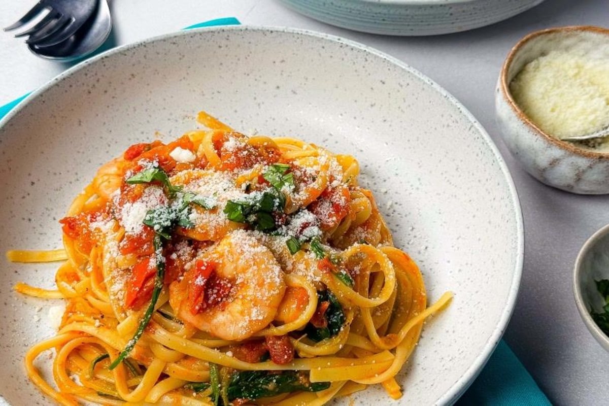 Linguine pasta with shrimp, tomato sauce, spinach, and grated cheese on top