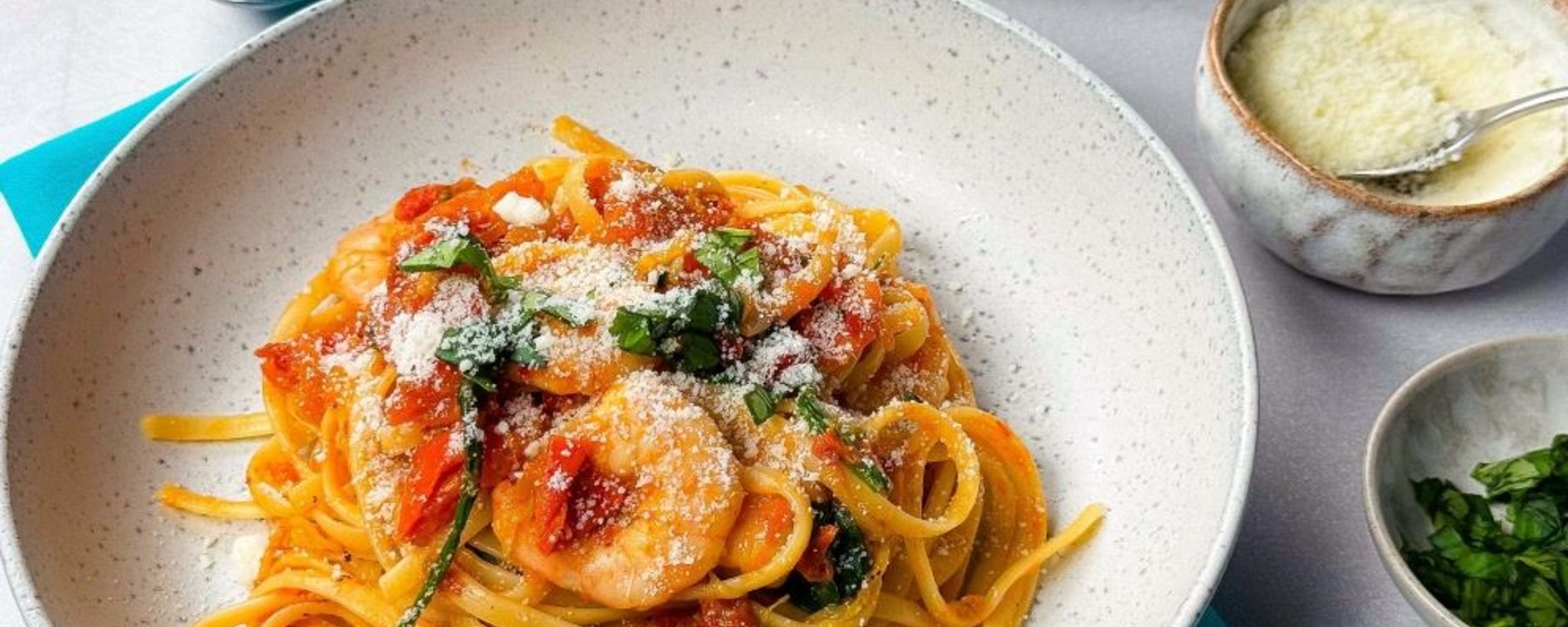 Linguine pasta with shrimp, tomato sauce, spinach, and grated cheese on top