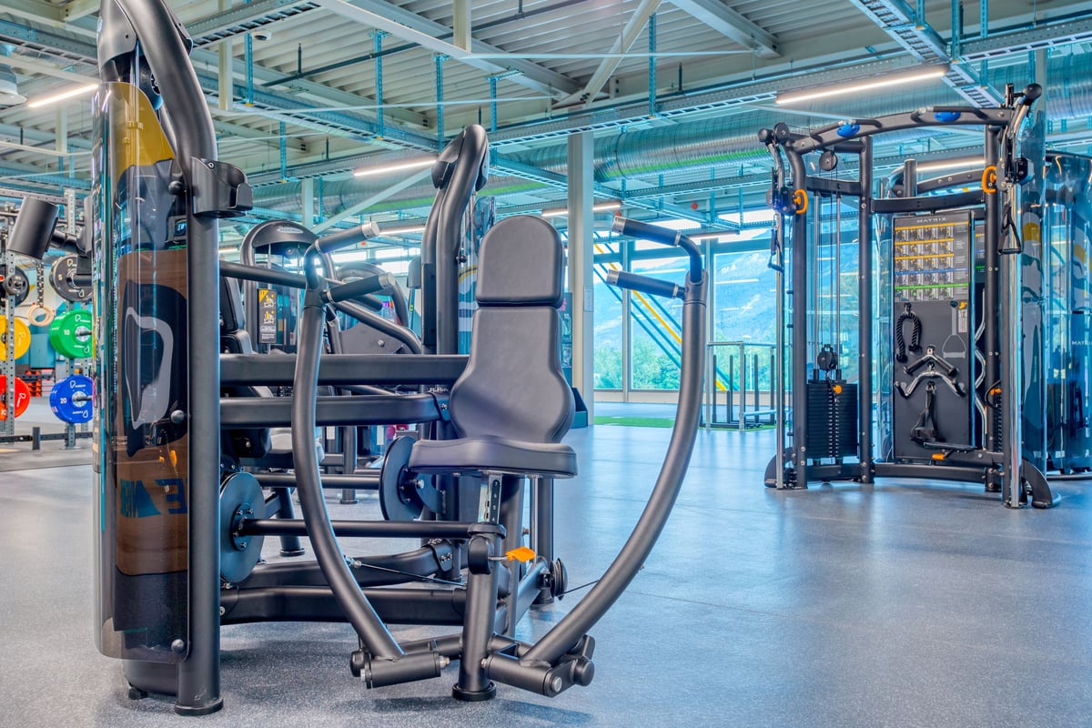 PureGym Martigny: Kraftgeräte, Kraftgeräte, Glaswände in einer Indoor-Trainingseinrichtung im industriellen Stil.