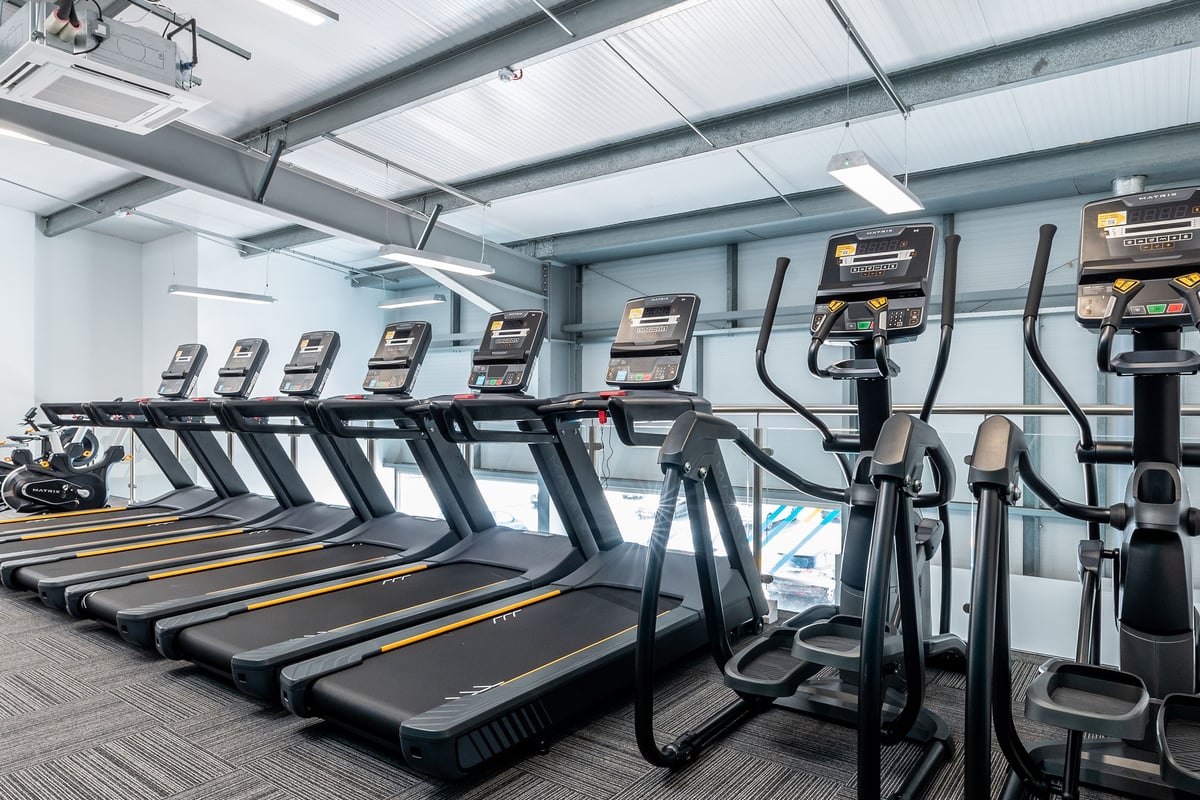 PureGym Sittingbourne: Rows of modern treadmills and elliptical cross-trainers in a brightly lit fitness facility.