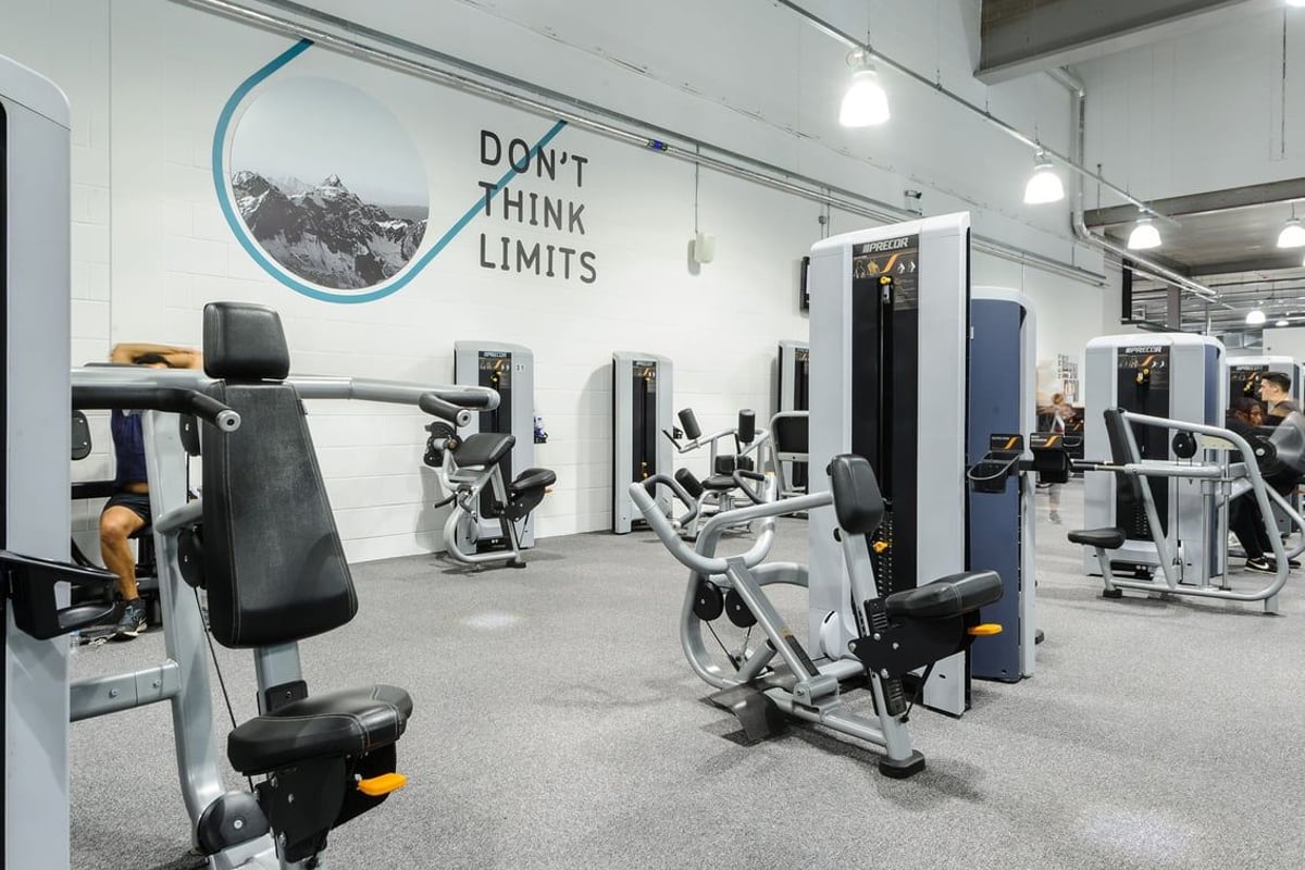 PureGym Bury: Rows of cardio machines, weight stations, and mirrored walls in a bright gym space with motivational signage.