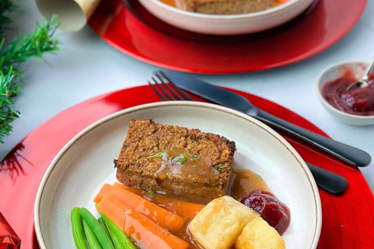 Vegan roast dinner with green beans, carrots, roast potatoes, gravy, and cranberry sauce o