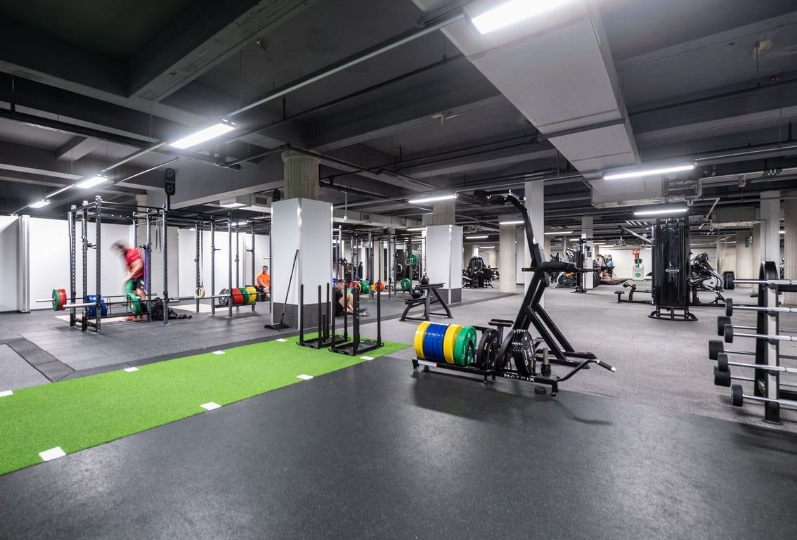 PureGym Liverpool Central: Gym with racks, free weights, green turf area, and rubberized flooring in industrial-style space.