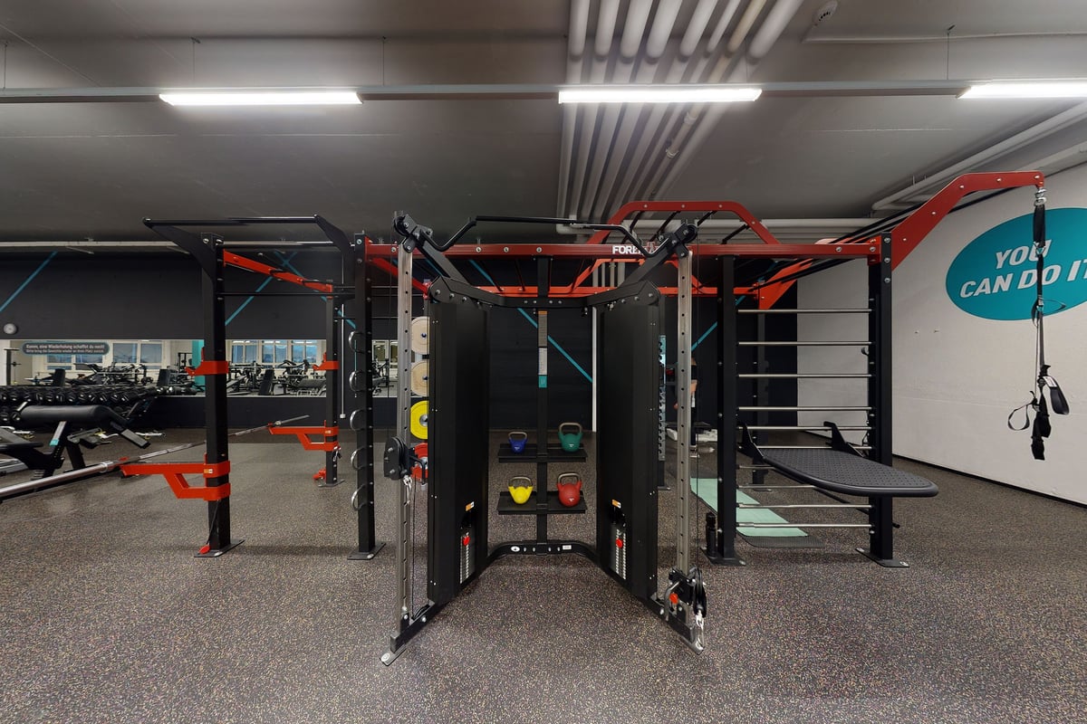 PureGym Kriens: Red functional training rig, rubberized flooring, stair climber, weights, and mirrored wall.