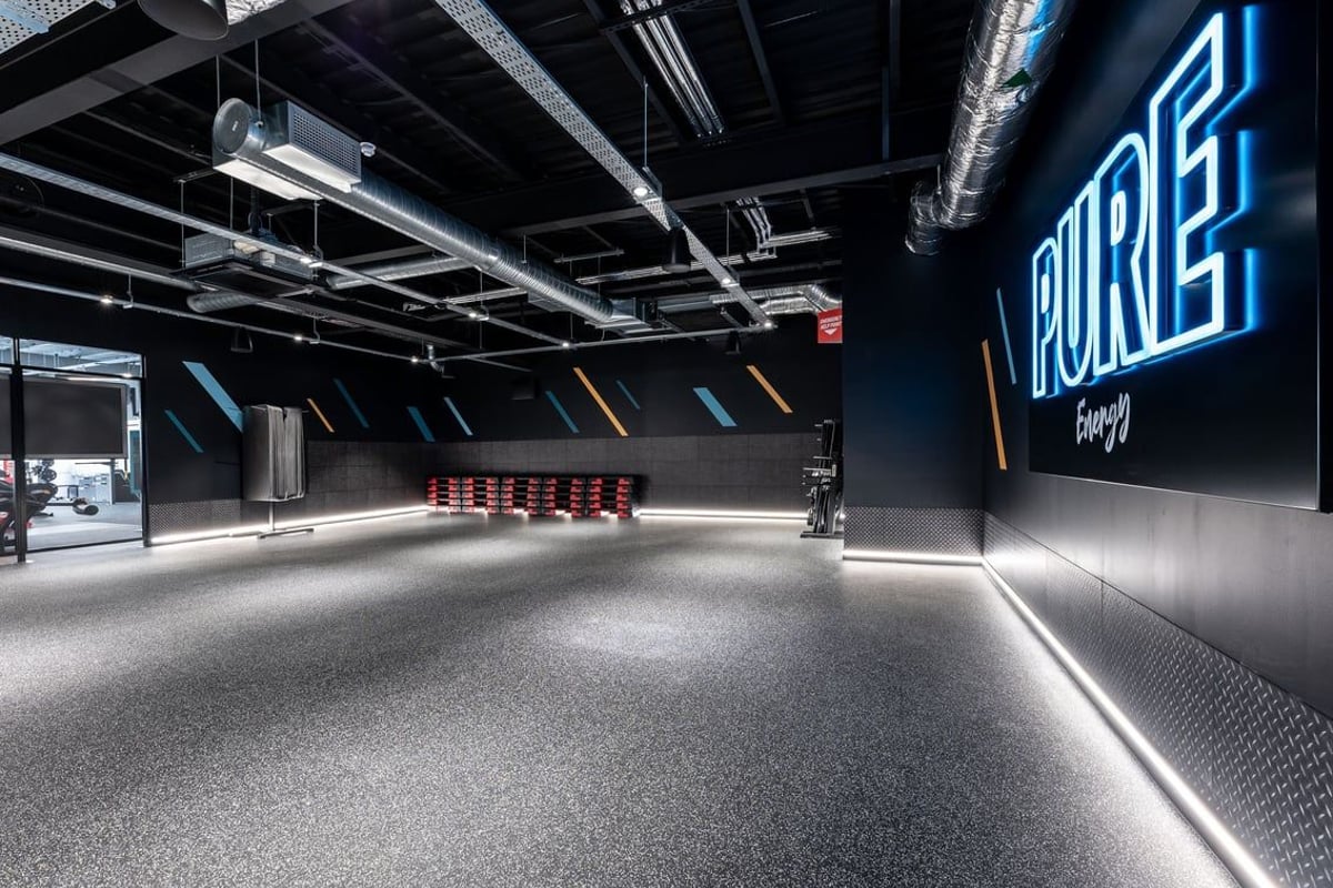 PureGym Yate: Rubberized flooring, neon signage, black interior with exposed ceiling and ductwork.