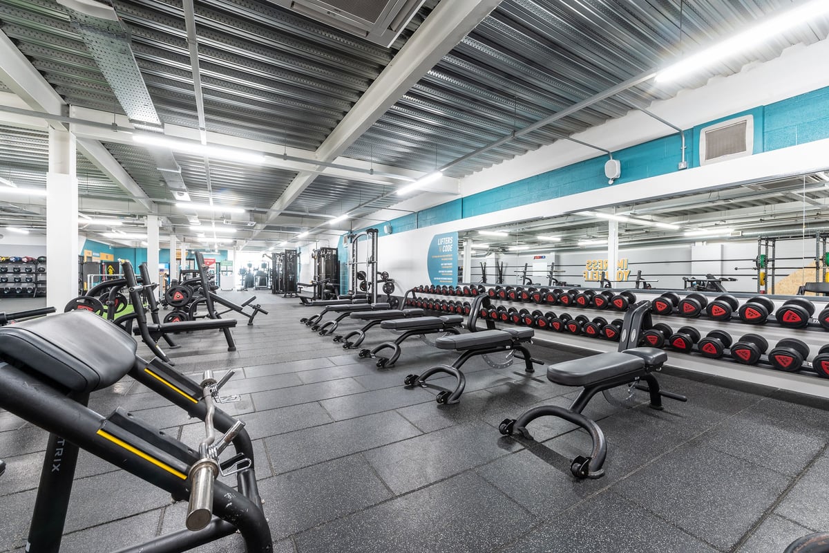 PureGym Banbury Cross Retail Park: Weightlifting area with benches, dumbbells, weight plates, and rubberized flooring.
