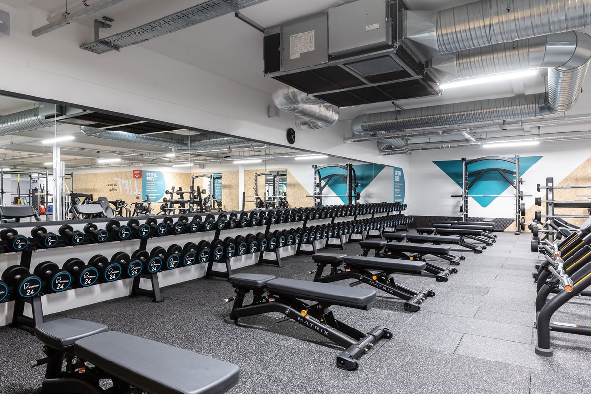 PureGym Bath Victoria Park: Rows of dumbbell racks, benches, free weights, and resistance equipment on rubberized flooring.
