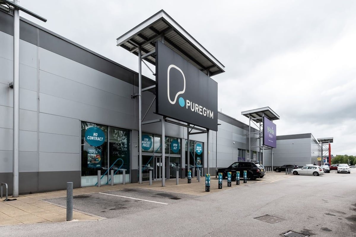 PureGym Oldham: Exterior of a modern gym building with signage and parking spaces.