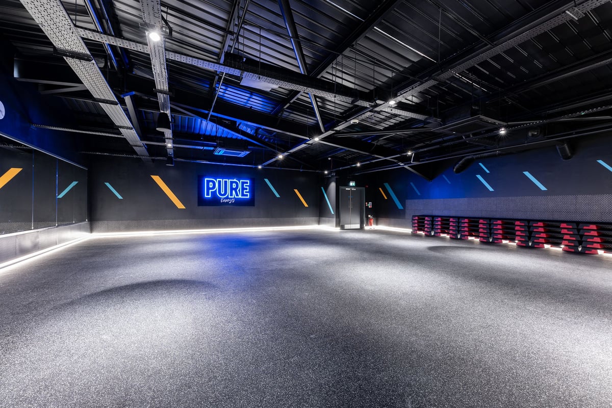 PureGym Broadstairs Westwood Gateway Retail Park: Studio with rubberized floor, neon signage, and stacks of step platforms.