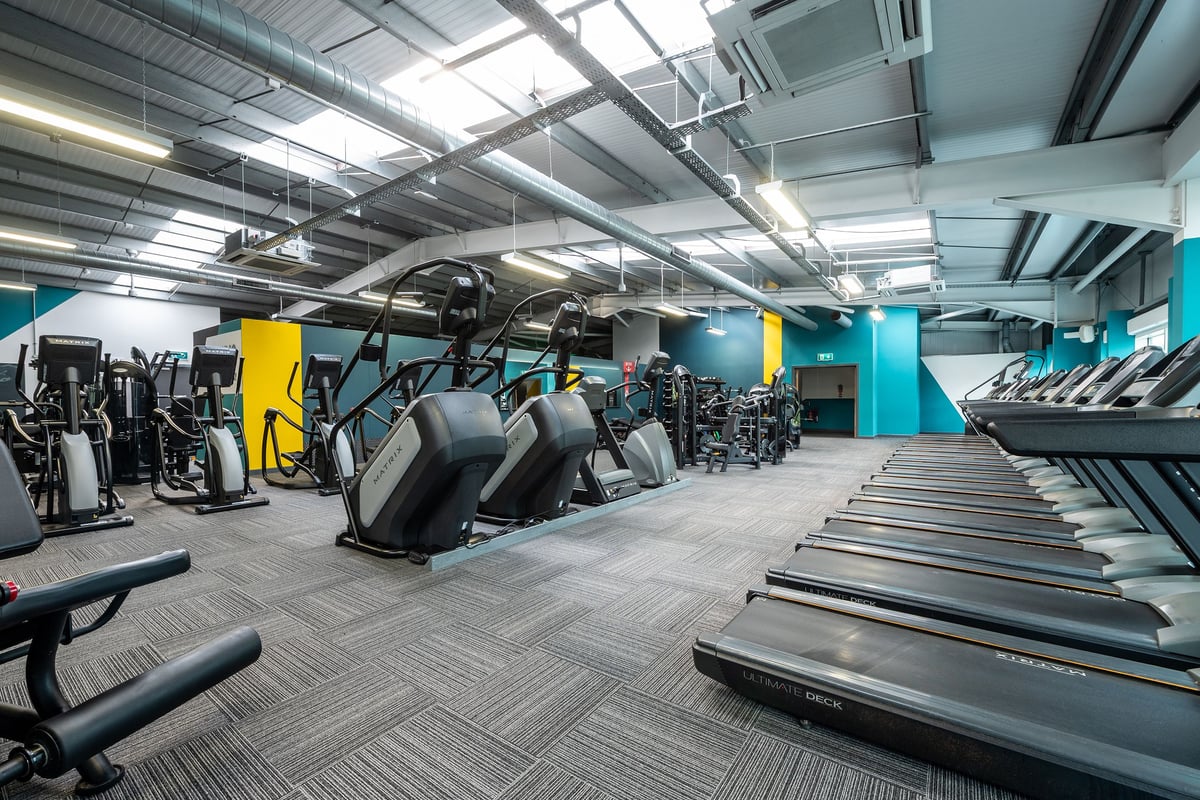 PureGym Wirral Bidston Moss: Rows of treadmills, ellipticals, weight machines, and free weights in a modern gym interior.
