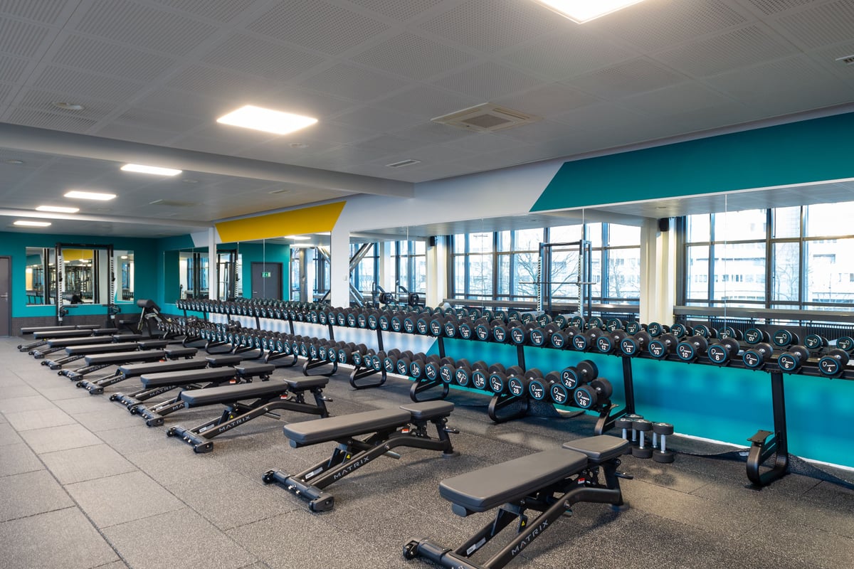 Espace poids libres de la gym Lochergut avec grand rack d'haltères et bancs