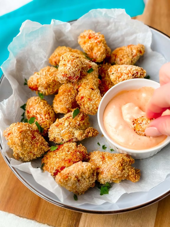 Breaded chicken nuggets with dipping sauce on parchment paper in a bowl