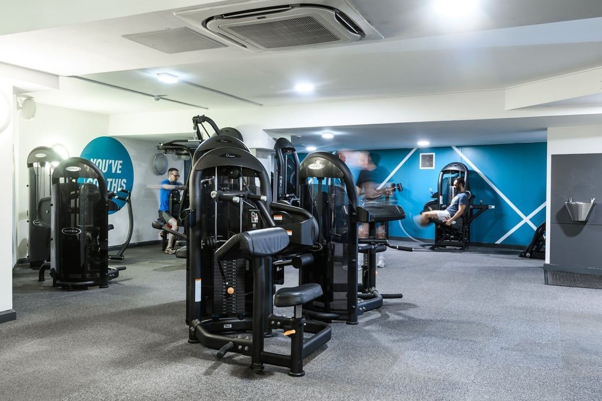 PureGym London St Pauls: Rows of strength training machines, free weights, mirrored walls, and blue branded accent walls.