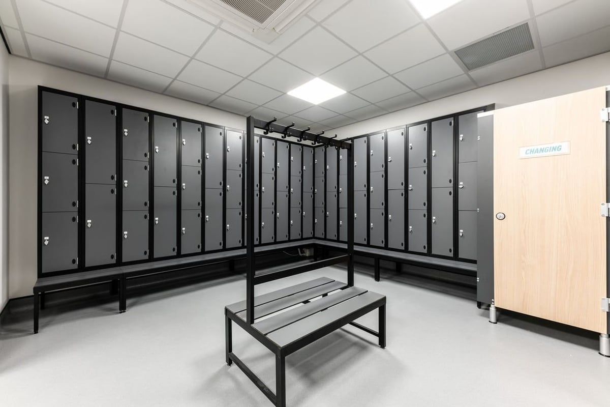 PureGym Kirkby: Rows of lockers, benches in a minimalist changing room interior.