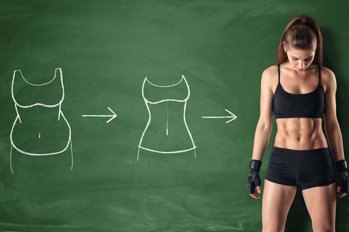 Fit woman in sportswear standing next to chalk drawings of slimming body transformations