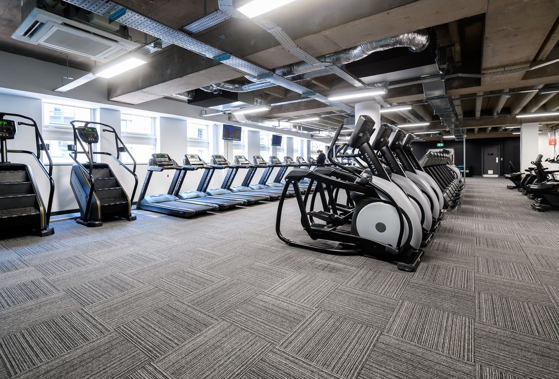 PureGym Birmingham Arcadian Centre: Rows of treadmills, stationary bikes, and other cardio machines in a modern gym setting.
