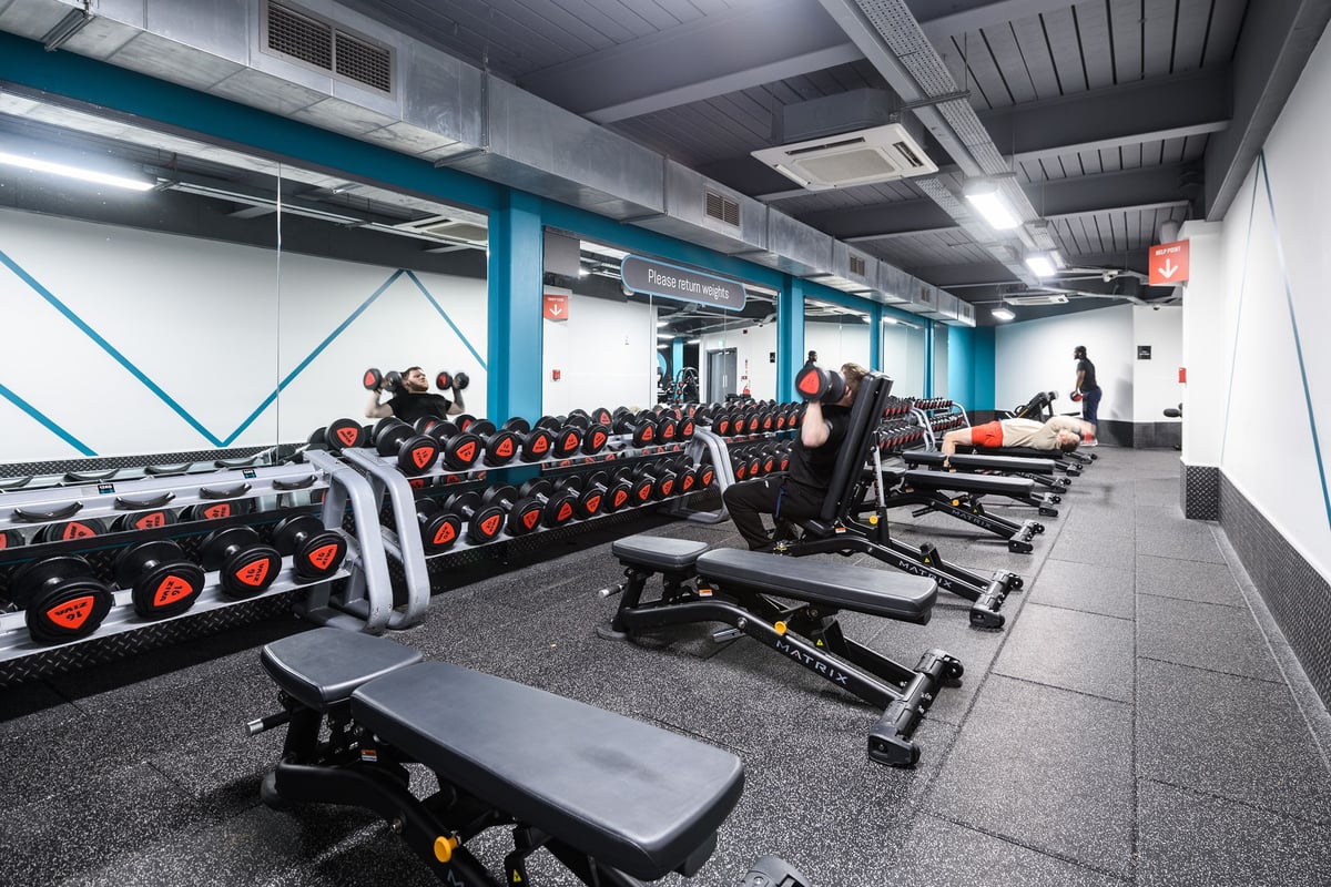 PureGym Northampton Central: Rows of weight machines, dumbbell racks, benches, and rubberized flooring in a gym setting.