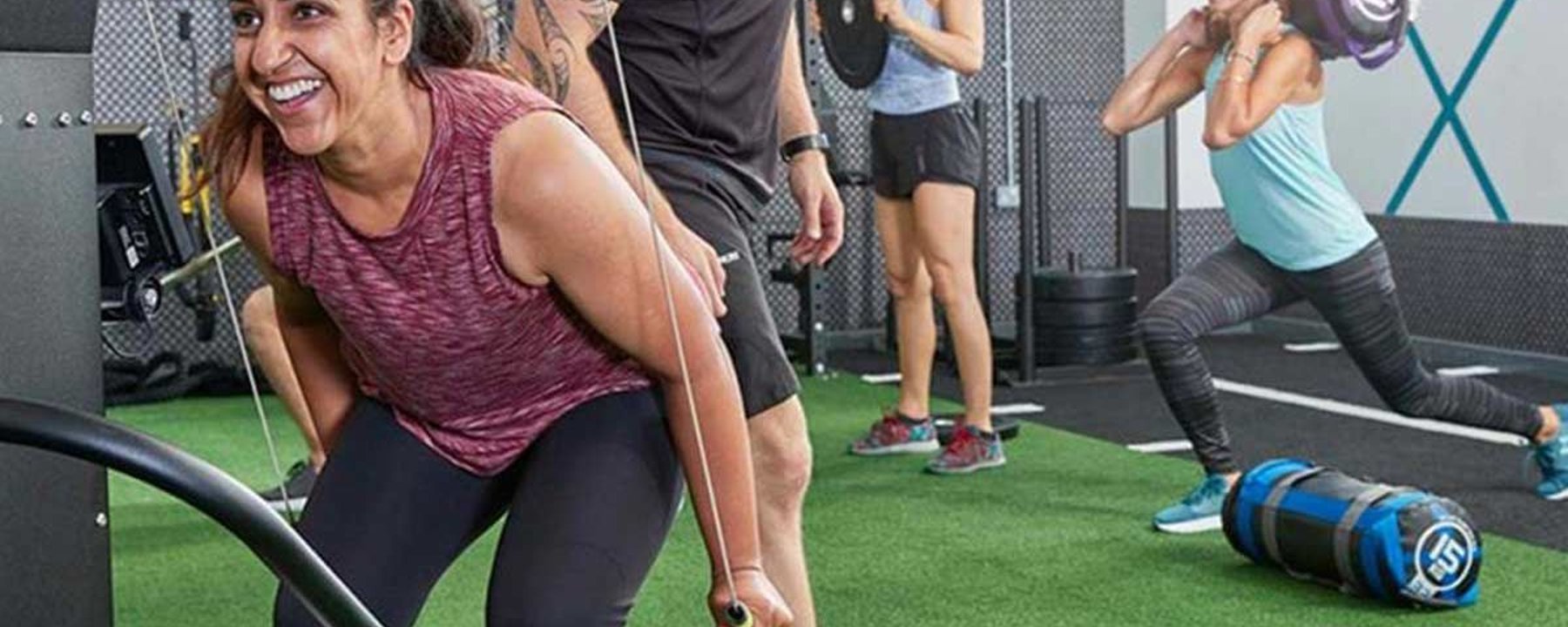 Femmes s'entraînant avec poids et câbles de résistance en salle, coach à proximité