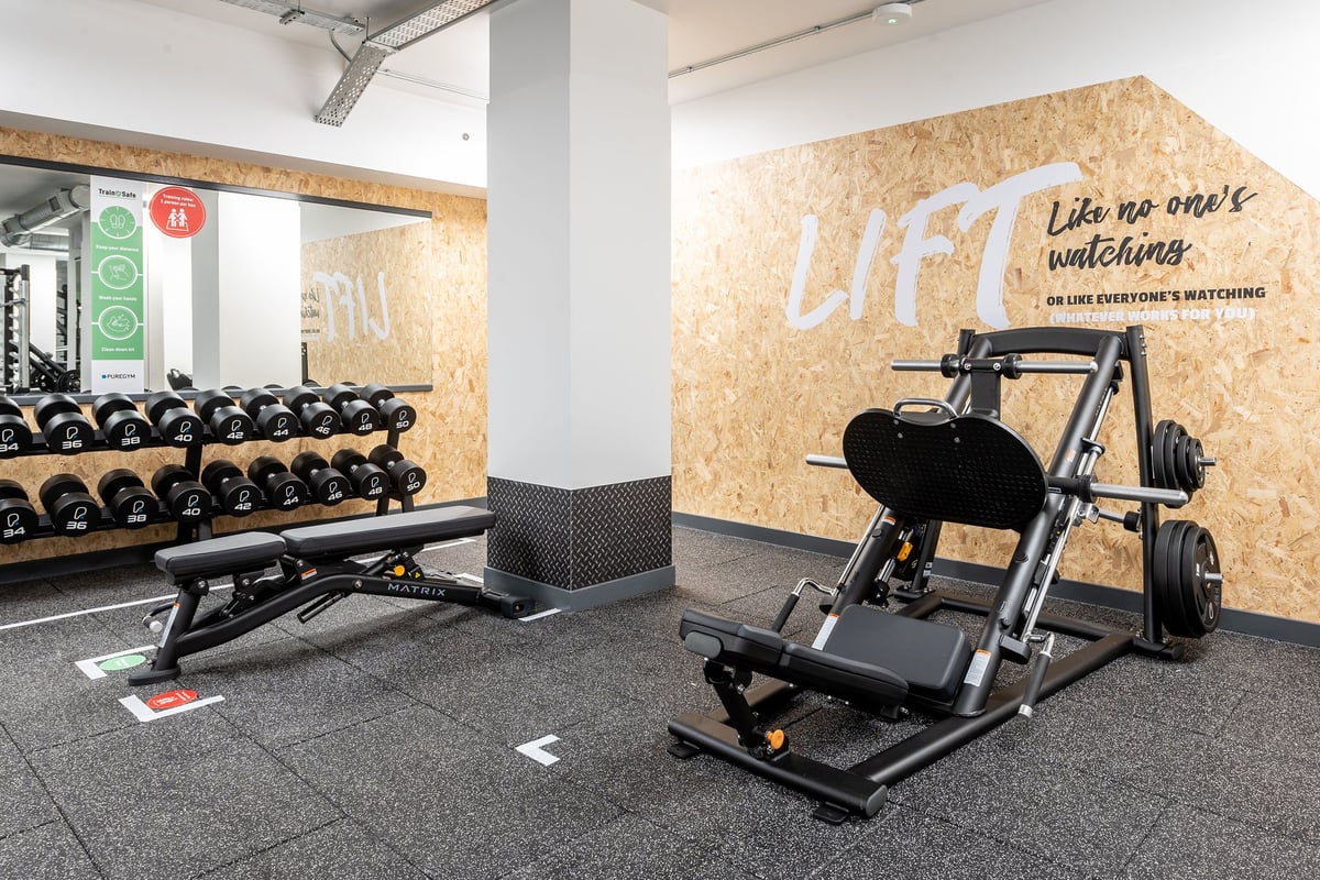 PureGym London Twickenham: Dumbbell racks, weight benches, cable machines on rubberized flooring near inspirational wall art.