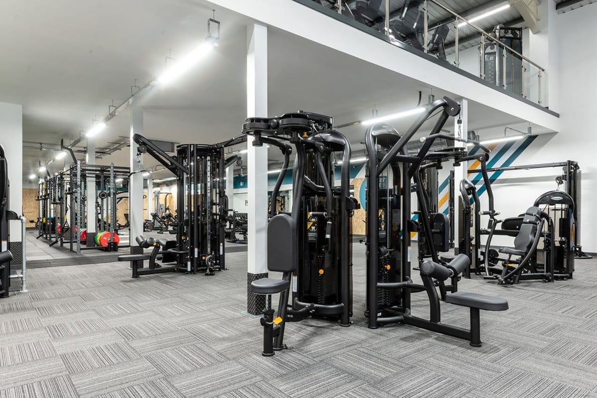 PureGym Macclesfield Silk Road: Gym weights machines, benches, mirrors, and rubberized flooring in a spacious fitness area.