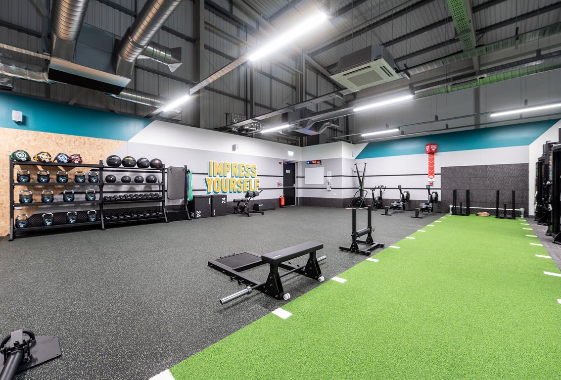 PureGym Sudbury: Weight racks, benches, tyres, turf area with weights and equipment for strength training.