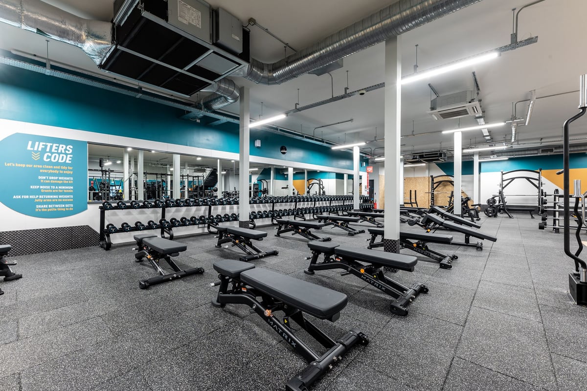 PureGym Watford Waterfields Retail Park: Strength training area with benches, free weights, racks, and rubberized flooring.
