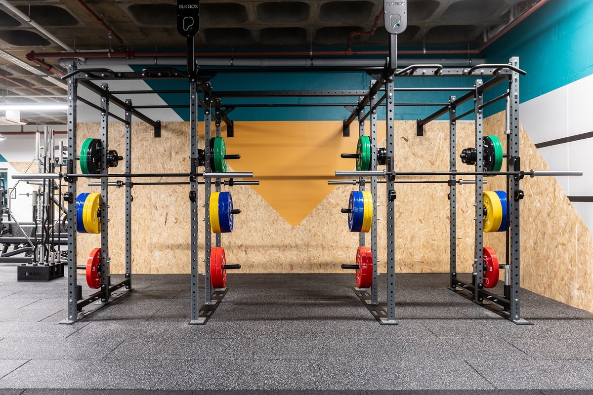 PureGym London Wood Green: Squat racks, weight plates in primary colours, rubberized flooring in a brightly lit space.