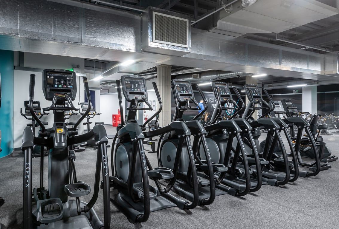 PureGym Liverpool Central: Rows of elliptical cross-trainers and treadmills in a basement gym setting.