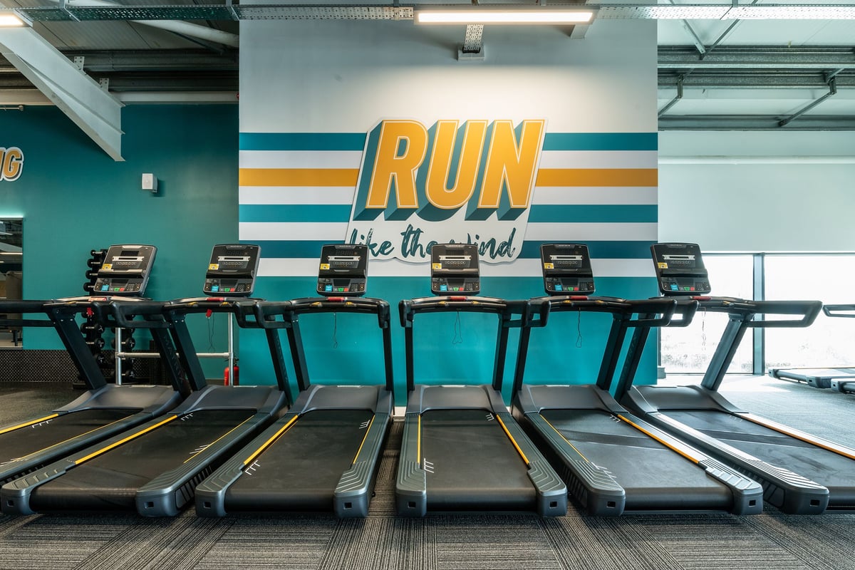 PureGym London Colney: Rows of treadmills with motivational slogan 'Run like the wind' on wall.