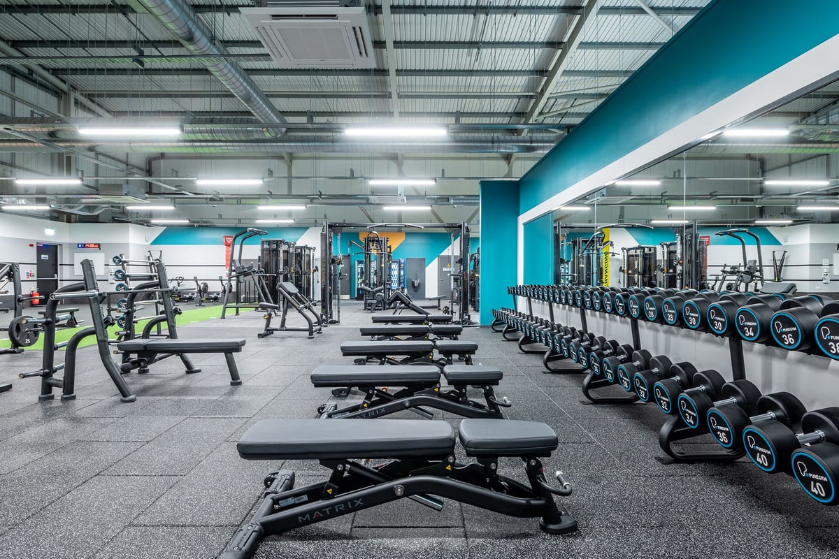 PureGym Sudbury: Weight benches, squat racks, dumbbells, barbells, and rubberized flooring in a modern gym setting.