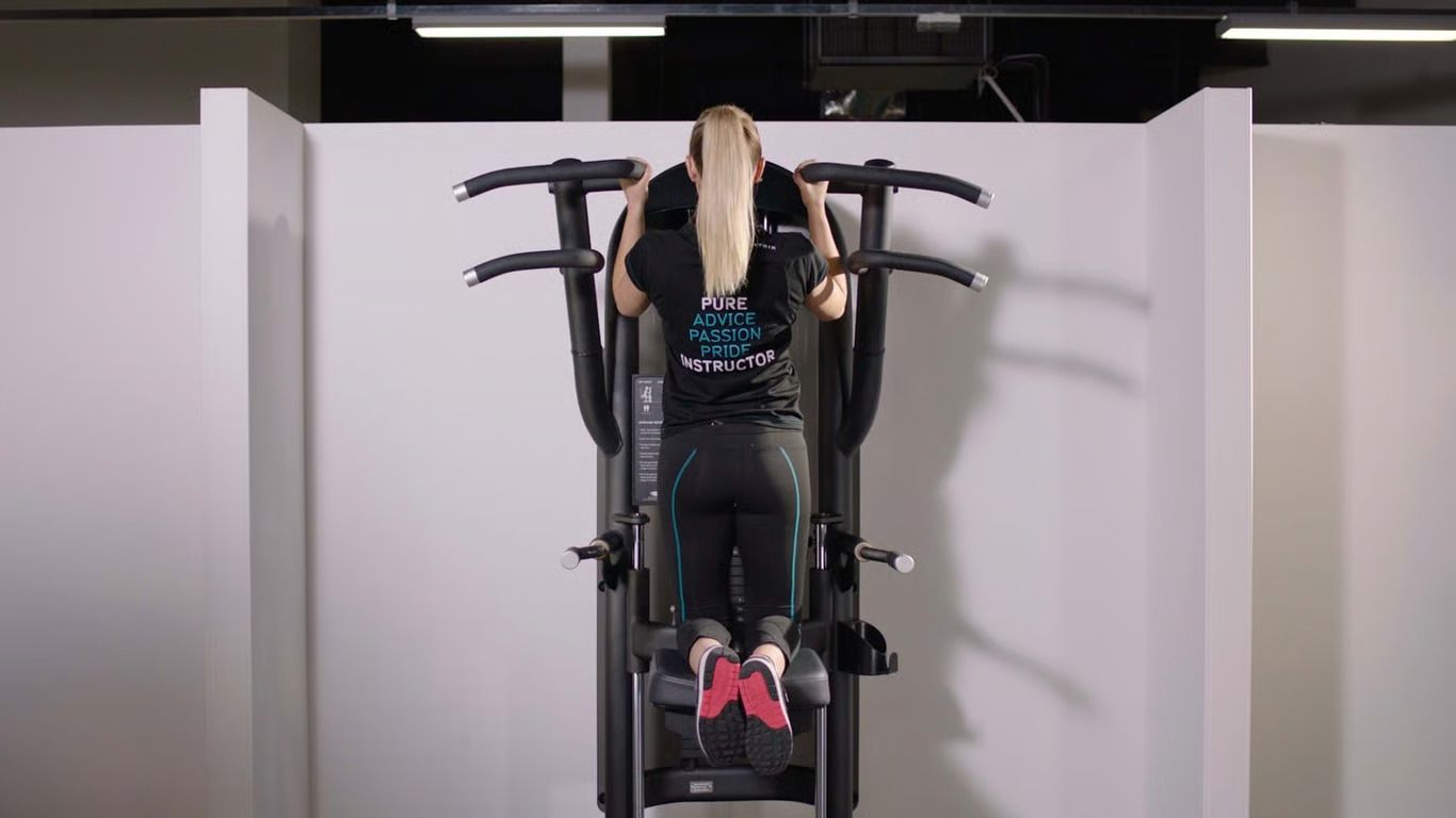 Woman using the assisted pull up machine