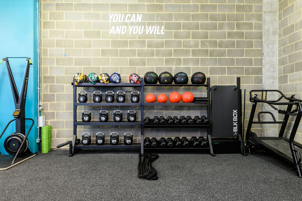 PureGym London Borough: Dumbbell racks, medicine ball trees, plyo boxes, rubberized flooring, motivational wall quote.