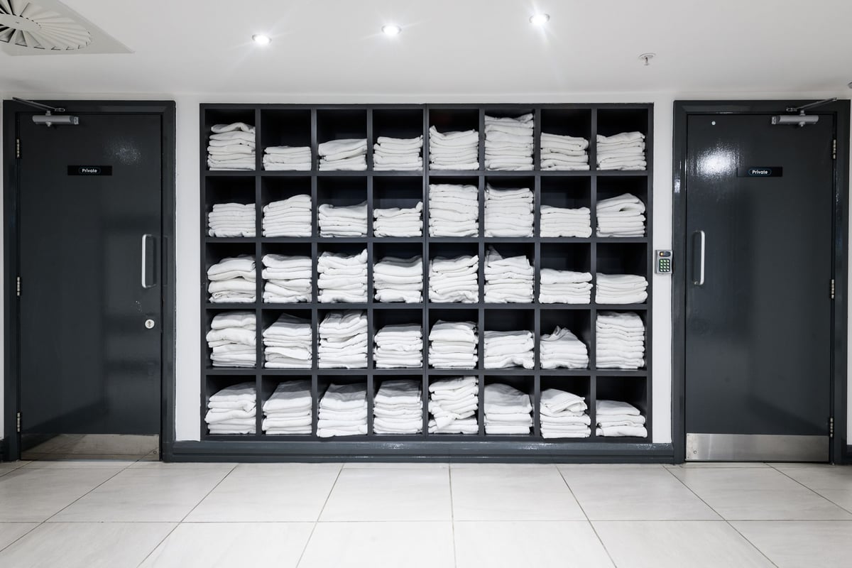 PureGym London Moorgate: Rows of towels neatly stacked on shelves behind closed cabinet doors.