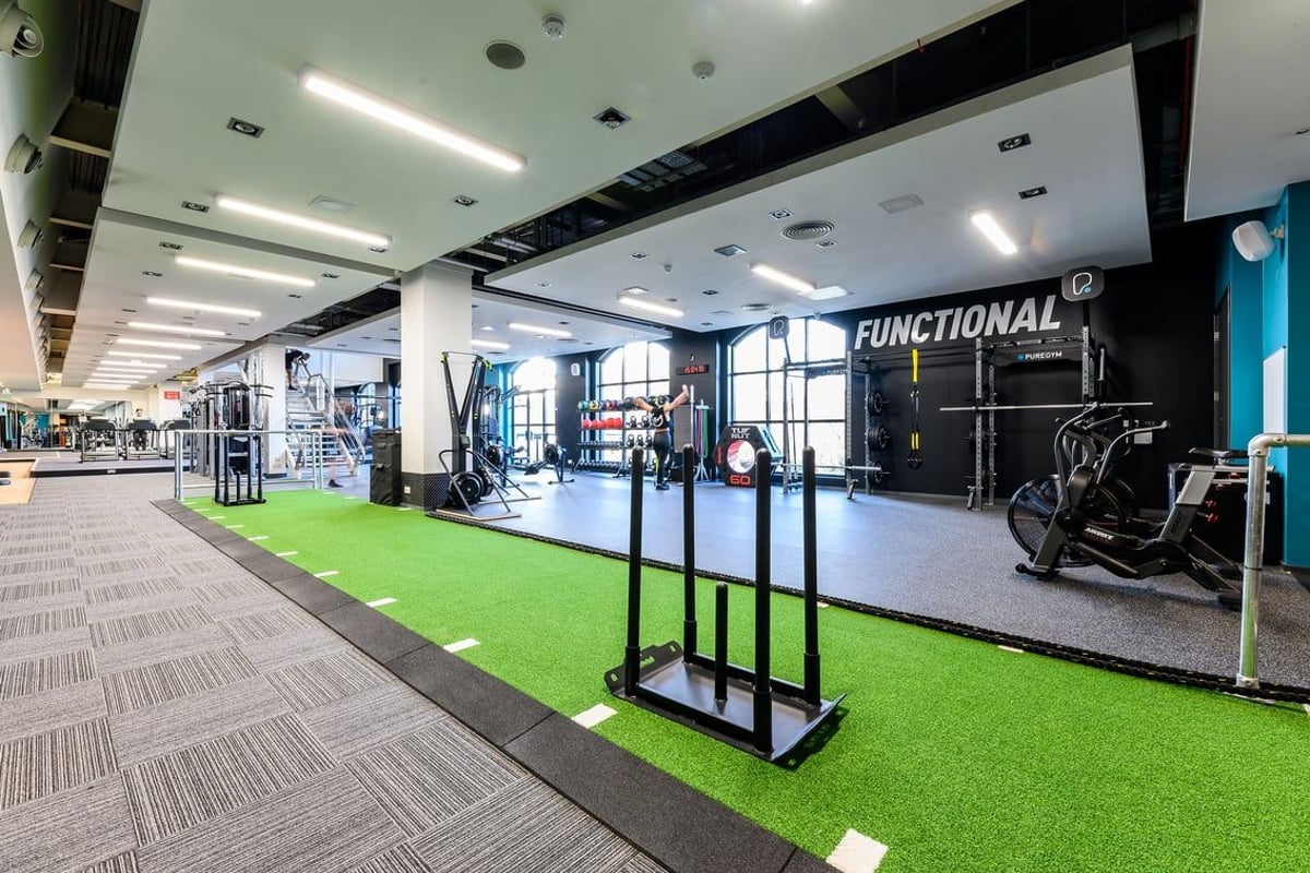 PureGym Norwich Riverside: Functional training area with squat racks, free weights, artificial turf flooring, and mirrors.
