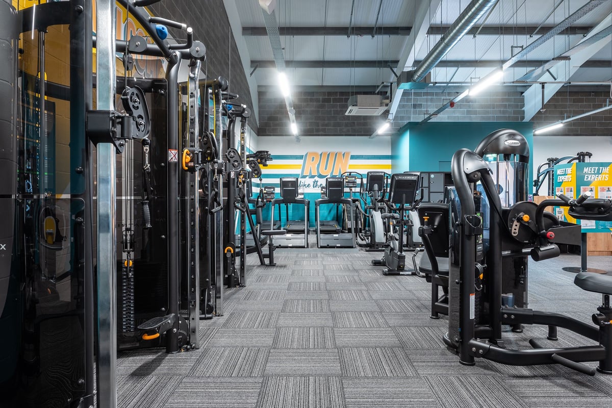 PureGym Aberdare: Rows of resistance machines, cable crossovers, plate-loaded equipment on rubberized flooring.